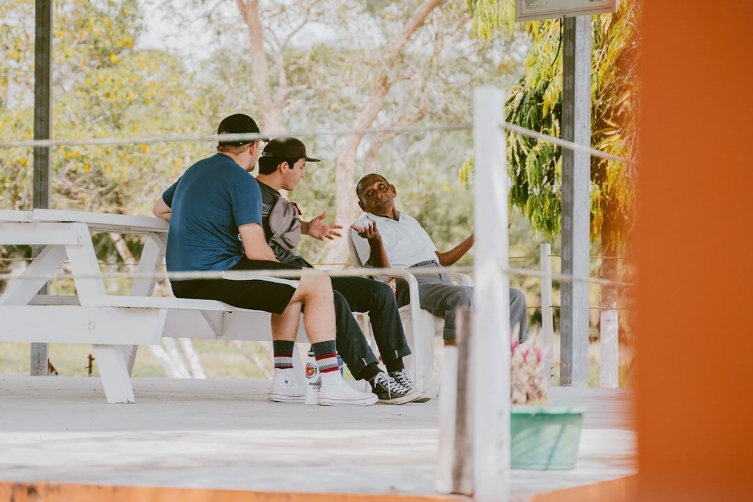 Group of seniors sitting outdoors on a bench chatting and smiling